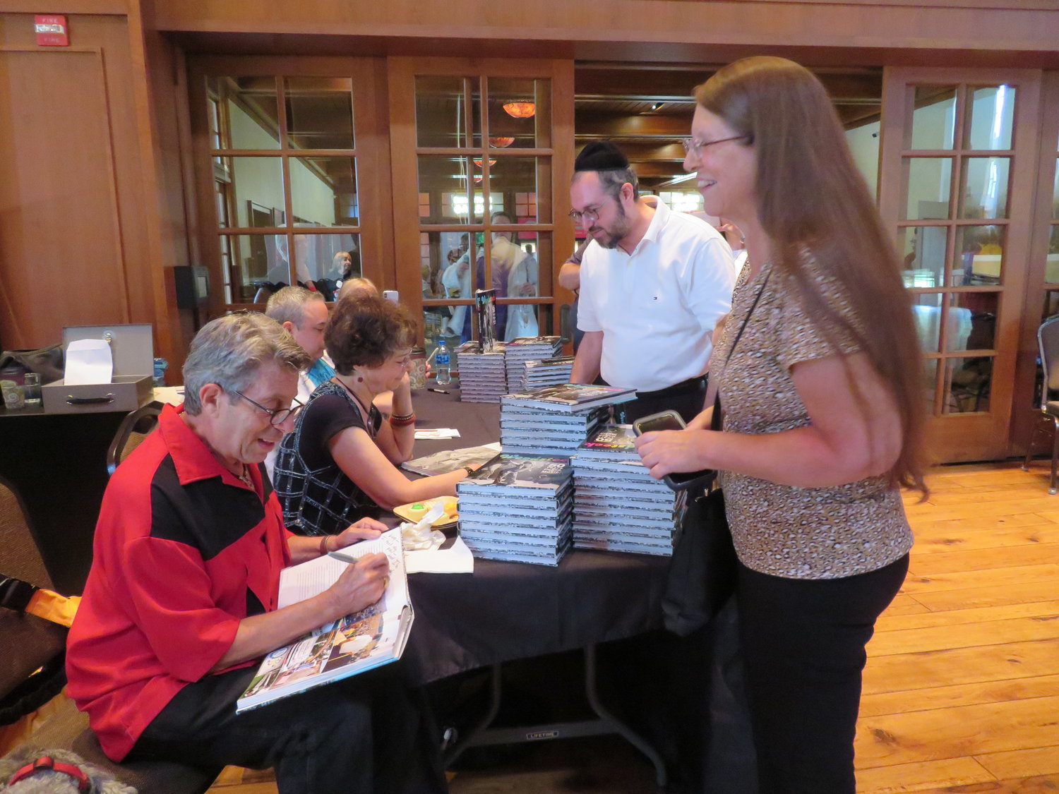 The panelists sign copies of “Woodstock: 50 Years of Peace and Music” after discussing the book and each of their connections to the iconc festival.